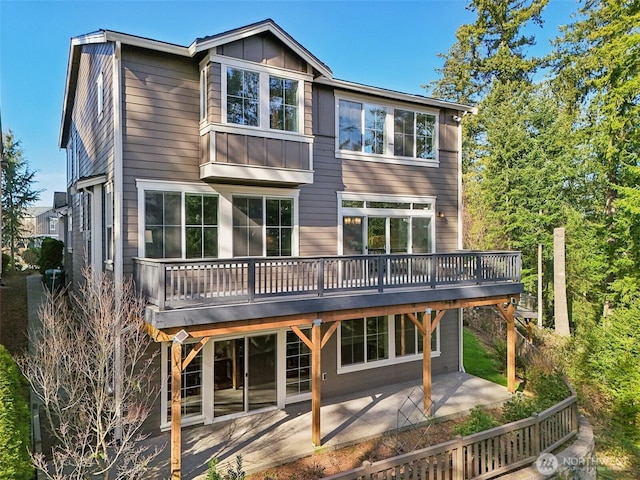 back of property featuring board and batten siding, a patio area, and a wooden deck