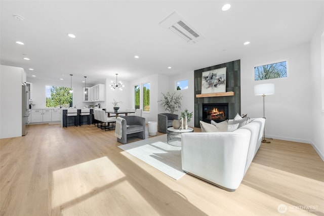 living room with a large fireplace, light wood finished floors, baseboards, a chandelier, and recessed lighting