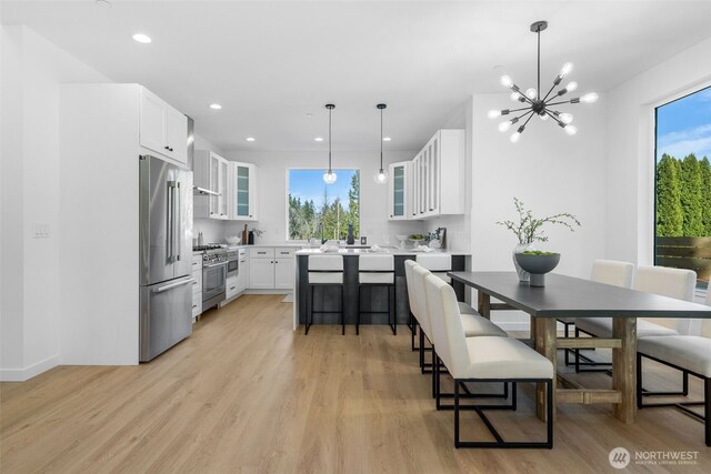 kitchen with high end appliances, light wood-type flooring, white cabinetry, and glass insert cabinets