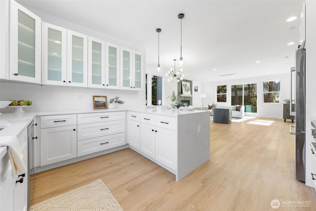 kitchen featuring open floor plan, white cabinetry, a peninsula, and light wood finished floors