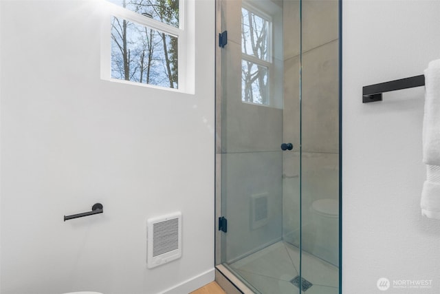 bathroom with a stall shower, visible vents, toilet, and baseboards