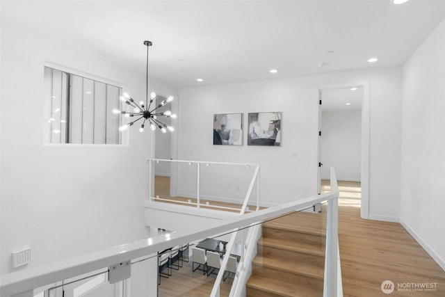 stairway with baseboards, recessed lighting, wood finished floors, and a notable chandelier