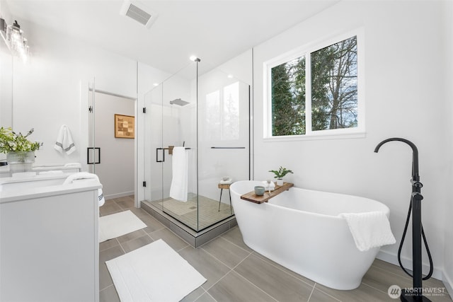 bathroom featuring a stall shower, baseboards, visible vents, a freestanding bath, and vanity