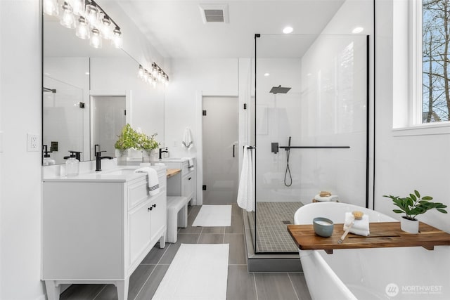 bathroom featuring visible vents, a stall shower, a soaking tub, and vanity