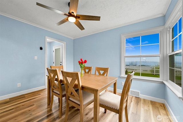 dining area with a ceiling fan, crown molding, baseboards, and light wood-type flooring