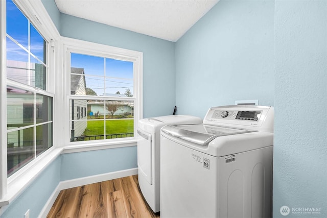 laundry area with wood finished floors, baseboards, washing machine and dryer, and laundry area