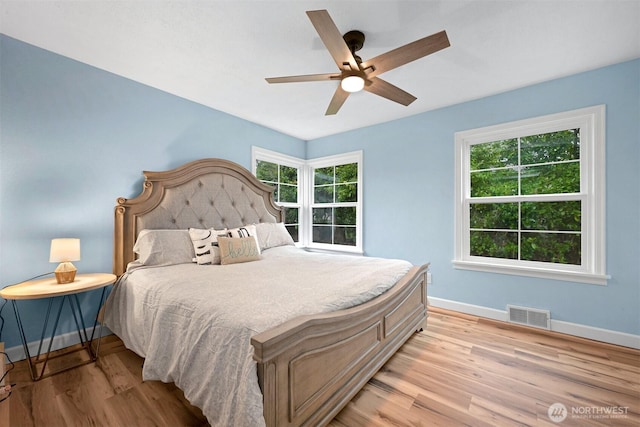 bedroom featuring a ceiling fan, light wood-style flooring, baseboards, and visible vents