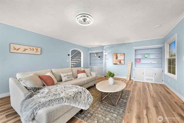 living room with baseboards, a textured ceiling, wood finished floors, and stairs