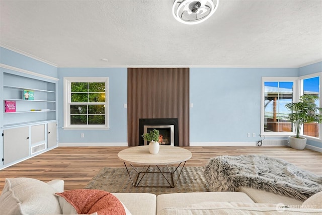 living room with visible vents, a textured ceiling, baseboards, and wood finished floors