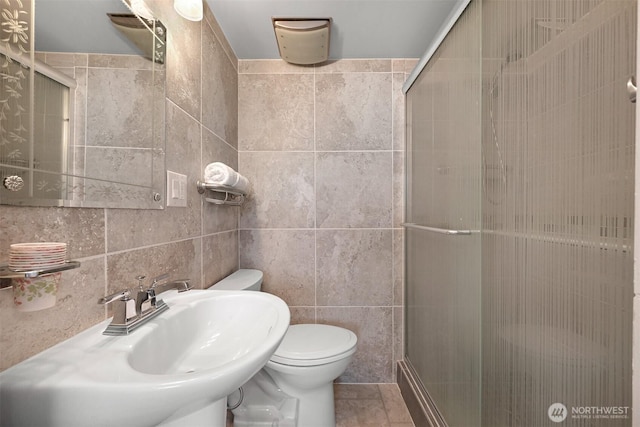 full bathroom featuring a stall shower, toilet, tile walls, and a sink