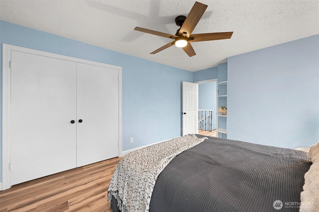 bedroom with a closet, light wood-style floors, a ceiling fan, and a textured ceiling