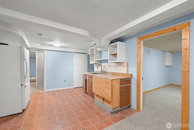 kitchen with baseboards, visible vents, open shelves, freestanding refrigerator, and a sink