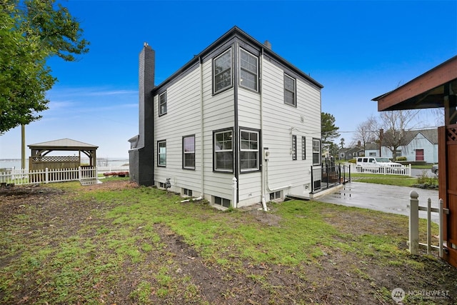 back of house featuring a gazebo, fence, a chimney, and a patio area