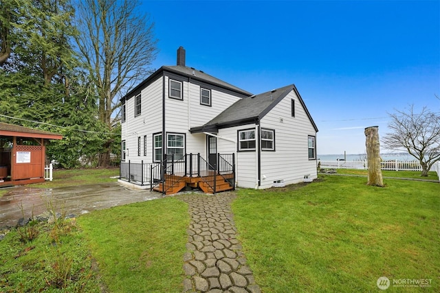 back of property with a yard, fence, a chimney, and aphalt driveway