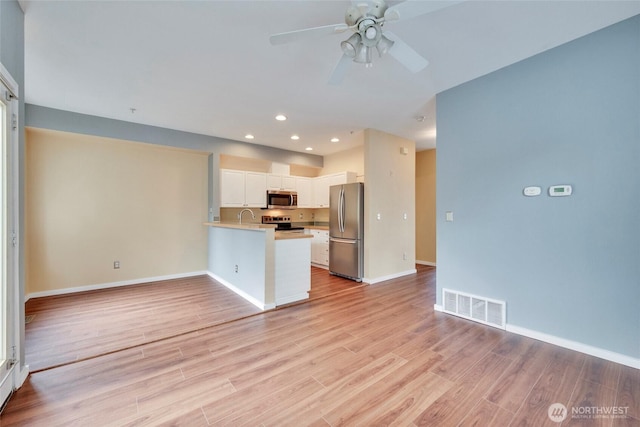 kitchen featuring stainless steel appliances, visible vents, open floor plan, light wood-type flooring, and a peninsula