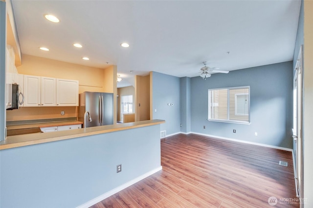 kitchen with appliances with stainless steel finishes, baseboards, white cabinetry, and light wood finished floors