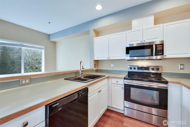 kitchen with white cabinetry, appliances with stainless steel finishes, light countertops, and a sink