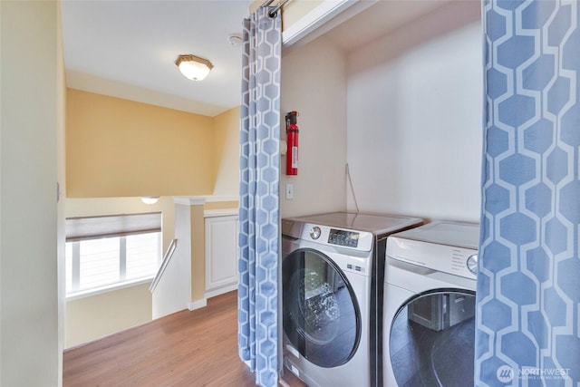 clothes washing area with laundry area, washing machine and dryer, and wood finished floors