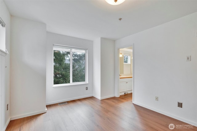 unfurnished room with wood finished floors, visible vents, and baseboards