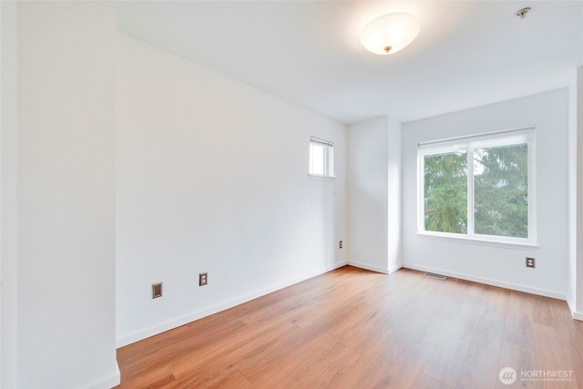 unfurnished room featuring light wood finished floors, baseboards, and visible vents