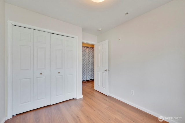 unfurnished bedroom with light wood finished floors, baseboards, and a closet