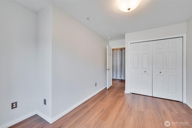 unfurnished bedroom with a closet, light wood-style flooring, and baseboards