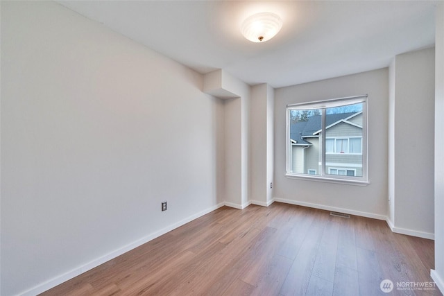 spare room with visible vents, baseboards, and wood finished floors