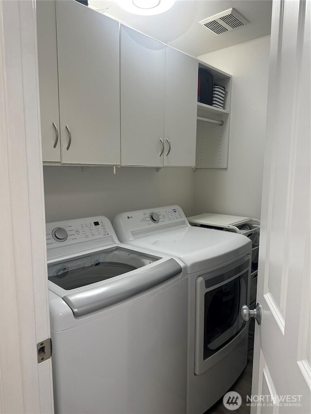 clothes washing area featuring cabinet space, visible vents, and independent washer and dryer