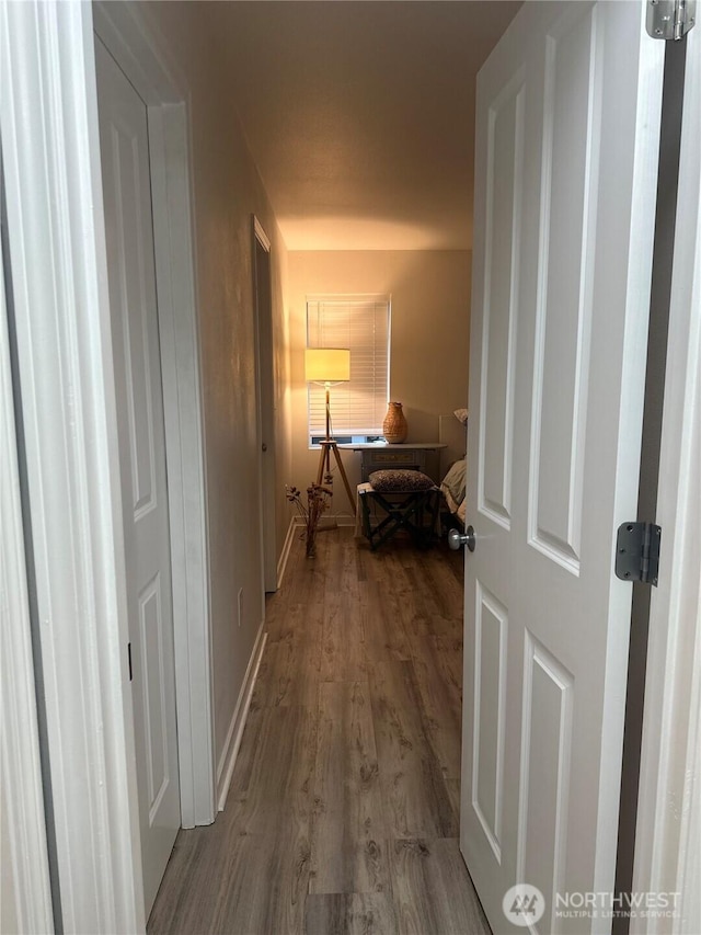 corridor featuring baseboards and wood finished floors