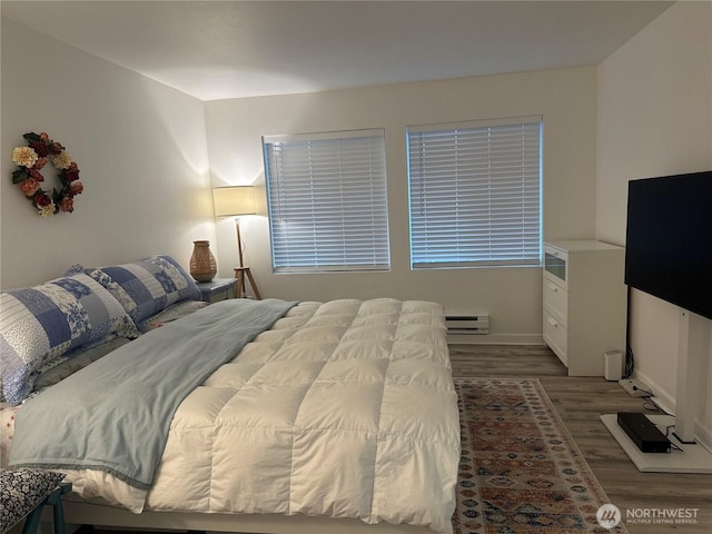 bedroom with wood finished floors, baseboards, and a baseboard radiator