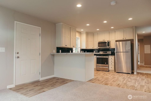 kitchen with stainless steel appliances, recessed lighting, light countertops, white cabinetry, and a peninsula