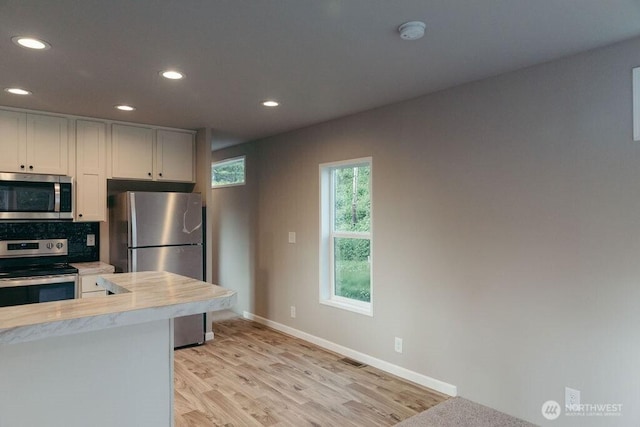 kitchen featuring recessed lighting, stainless steel appliances, white cabinetry, light wood-style floors, and tasteful backsplash