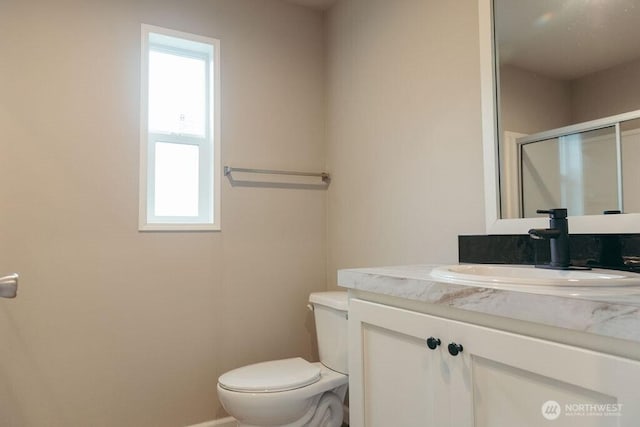 bathroom with toilet, vanity, and a shower stall