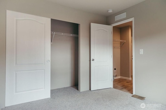 unfurnished bedroom with visible vents, a closet, and light colored carpet