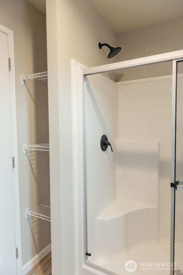 full bathroom with a shower stall and baseboards