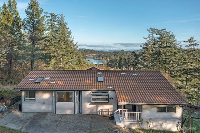 view of front of property with a tiled roof, a patio, and a water view