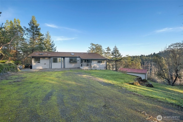 rear view of property with metal roof and a lawn