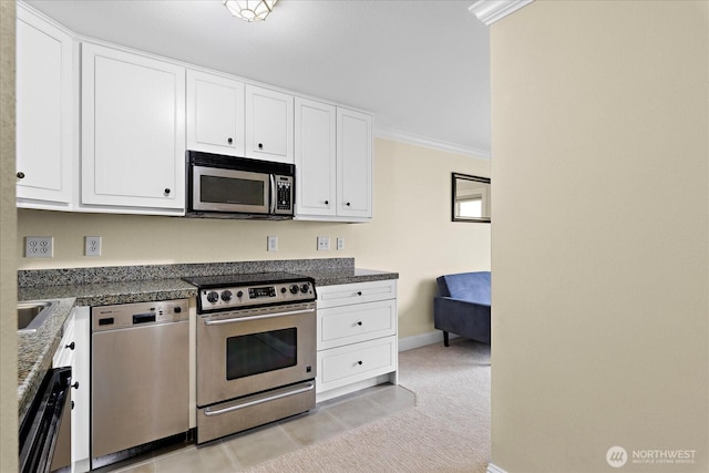 kitchen with white cabinets, light carpet, ornamental molding, and stainless steel appliances