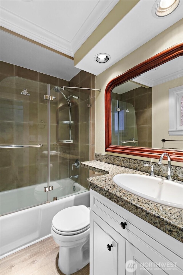 full bath with toilet, ornamental molding, enclosed tub / shower combo, vanity, and wood finished floors