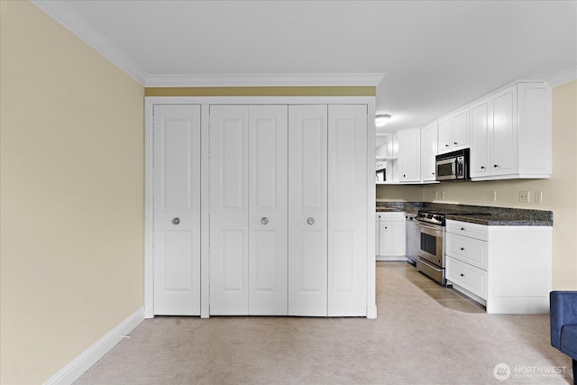 kitchen with stainless steel appliances, dark countertops, white cabinets, and light carpet