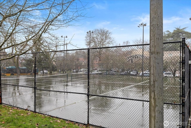 view of sport court with a tennis court and fence