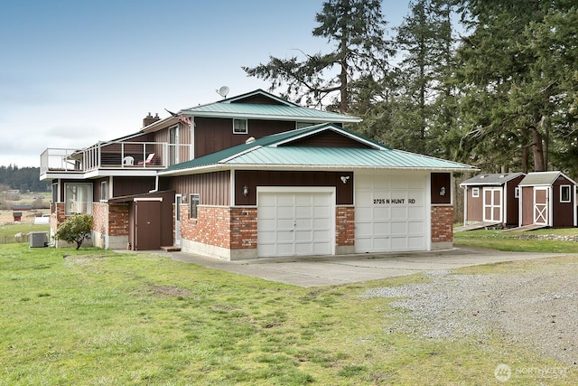 view of front of house featuring concrete driveway, a storage shed, central AC unit, metal roof, and a front lawn