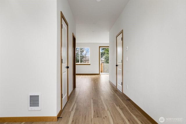 hall featuring baseboards, visible vents, and light wood-style floors