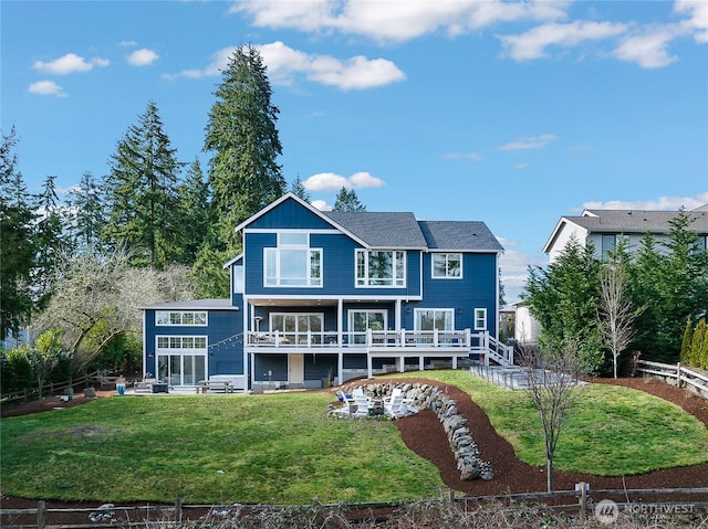 rear view of house featuring a yard, a deck, and fence