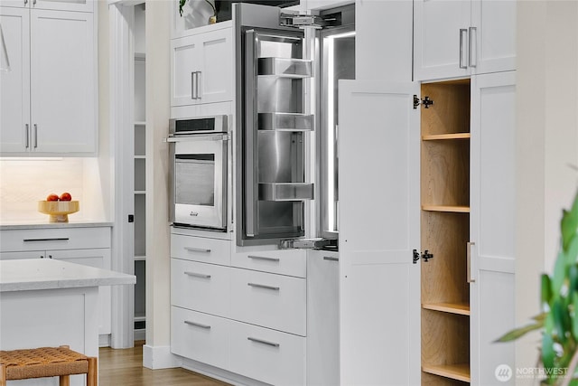 interior space featuring light countertops, white cabinets, stainless steel oven, and open shelves