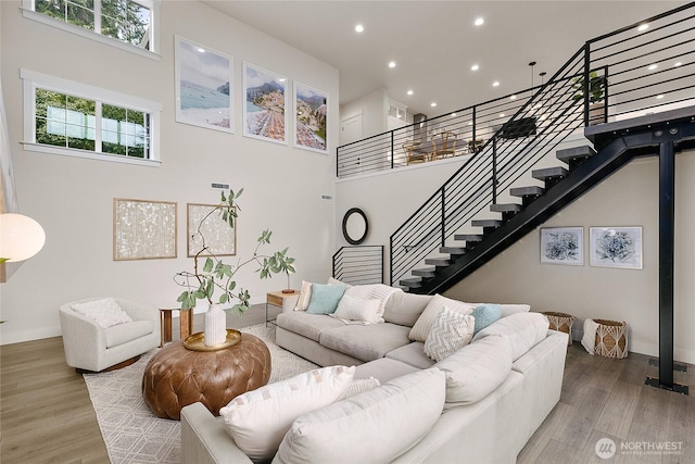 living room featuring light wood-style floors, stairs, and a high ceiling