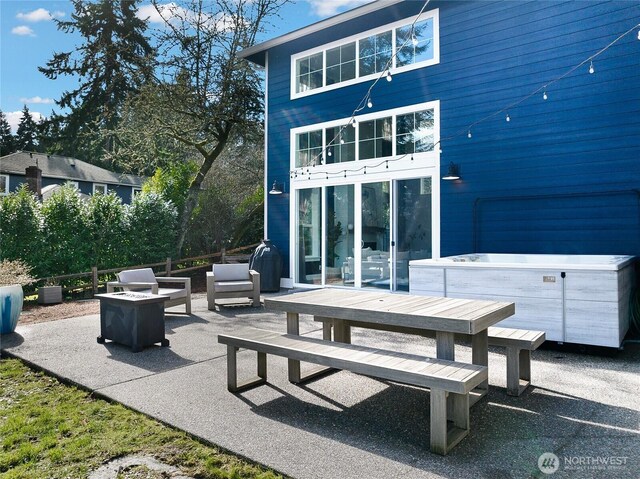 rear view of property featuring an outdoor living space with a fire pit