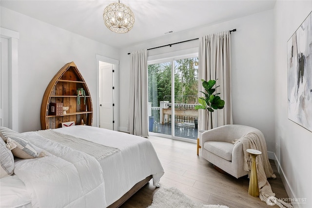 bedroom featuring access to exterior, a notable chandelier, visible vents, wood finished floors, and baseboards