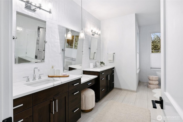 full bathroom with tasteful backsplash, tile walls, two vanities, and a sink