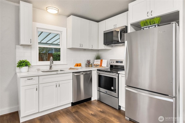 kitchen with light countertops, appliances with stainless steel finishes, a sink, and white cabinets